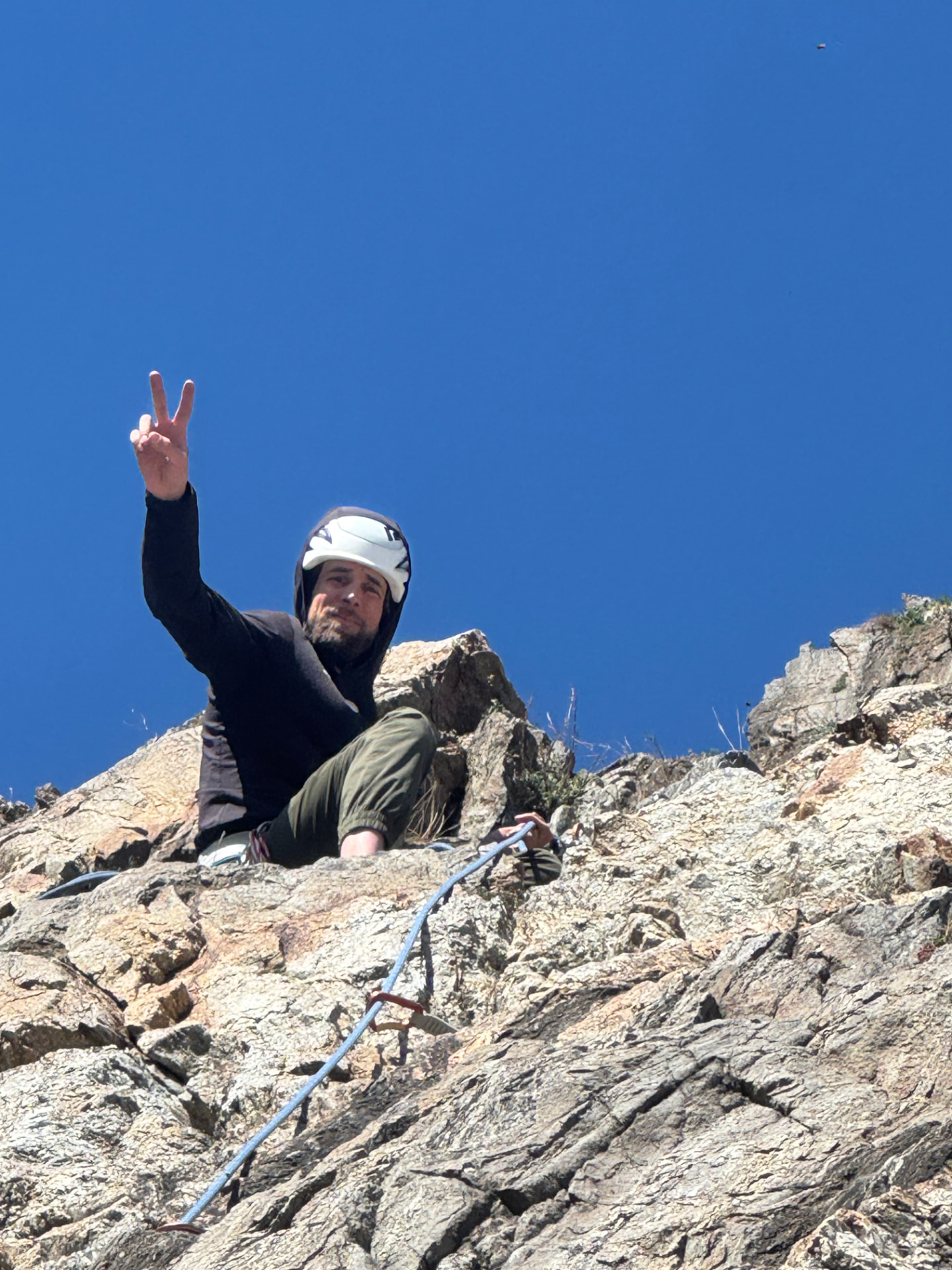 Quentin au relais en haut d'une voie d'escalade, faisant le signe de la victoire