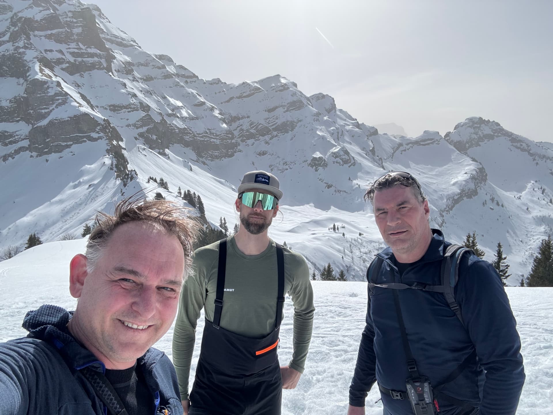 Quentin et deux clients en course de ski de randonnée devant un massif enneigé